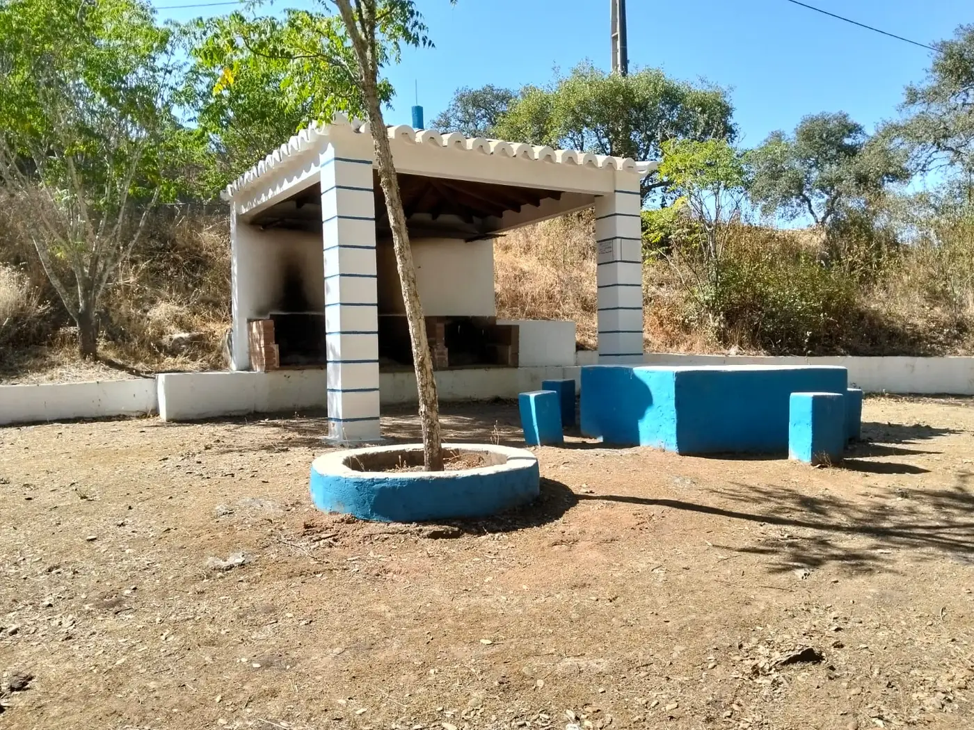 Telheiro caiado de branco e azul com as churrasqueiras de tijolo do parque